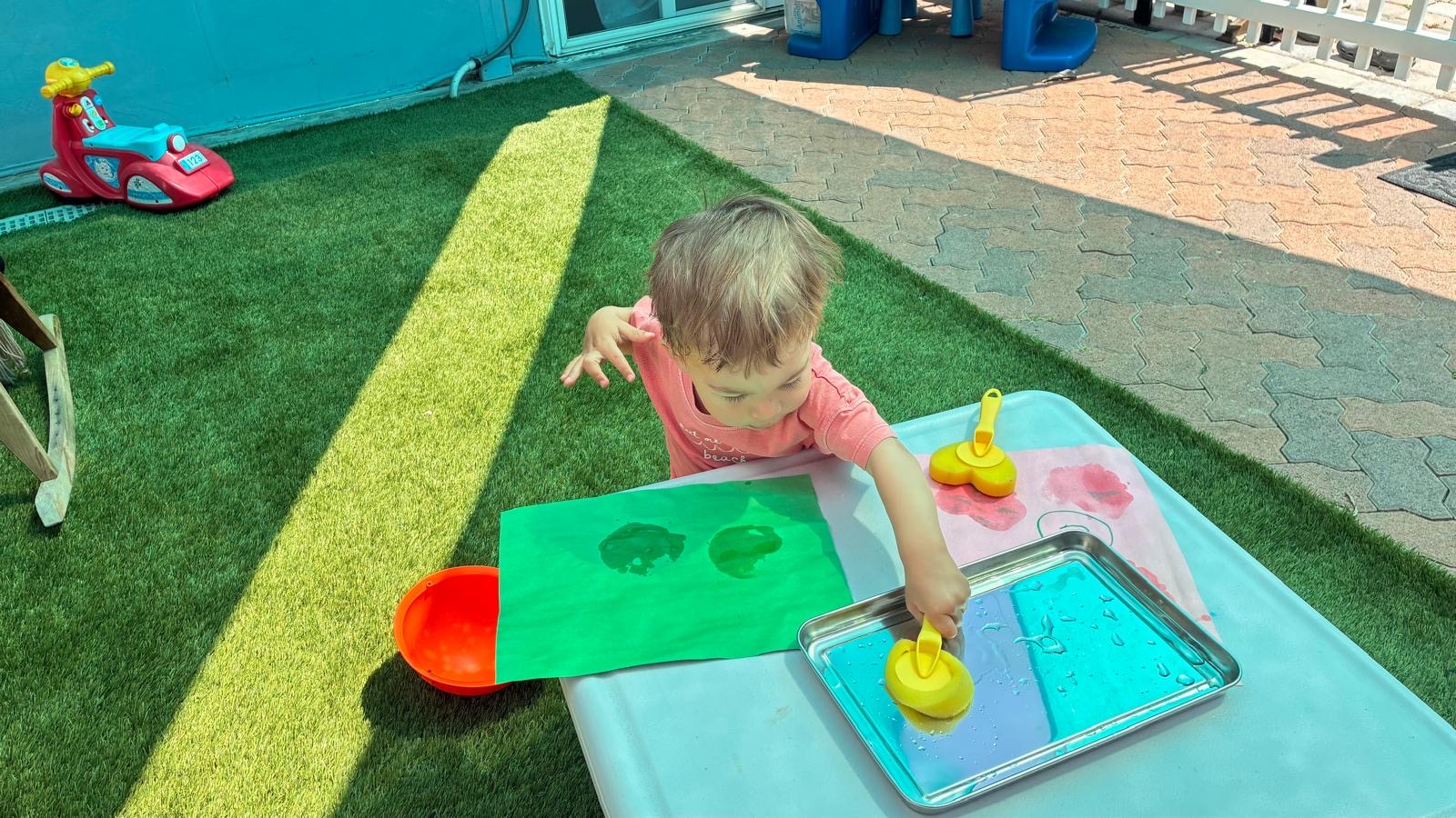 Child painting outside at a small activity table