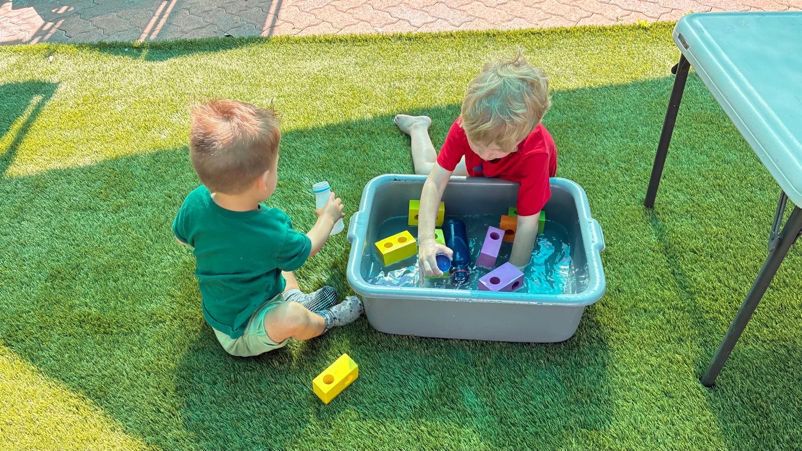 Children doing outdoor water play on the daycare turf